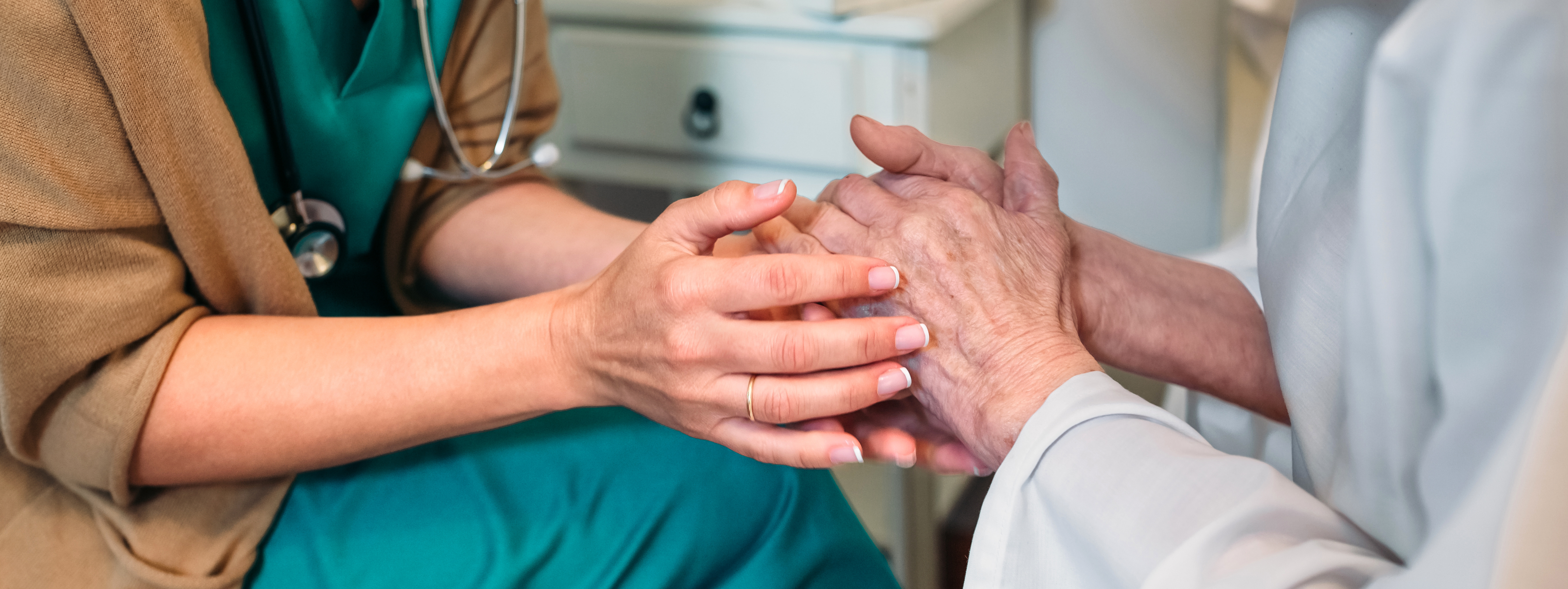 A close-up of a doctor holding an old person's hand